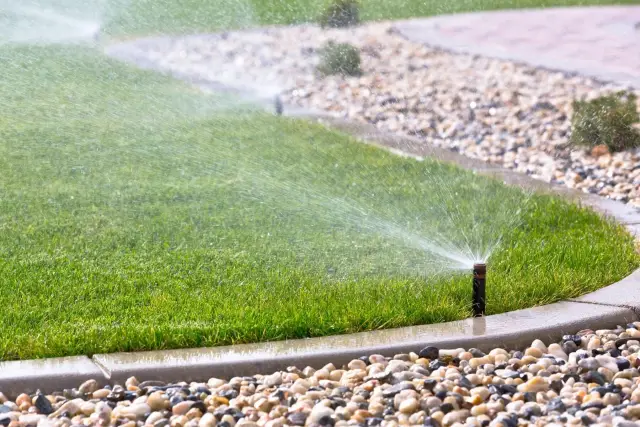A healthy lawn being evenly watered by a sprinkler system