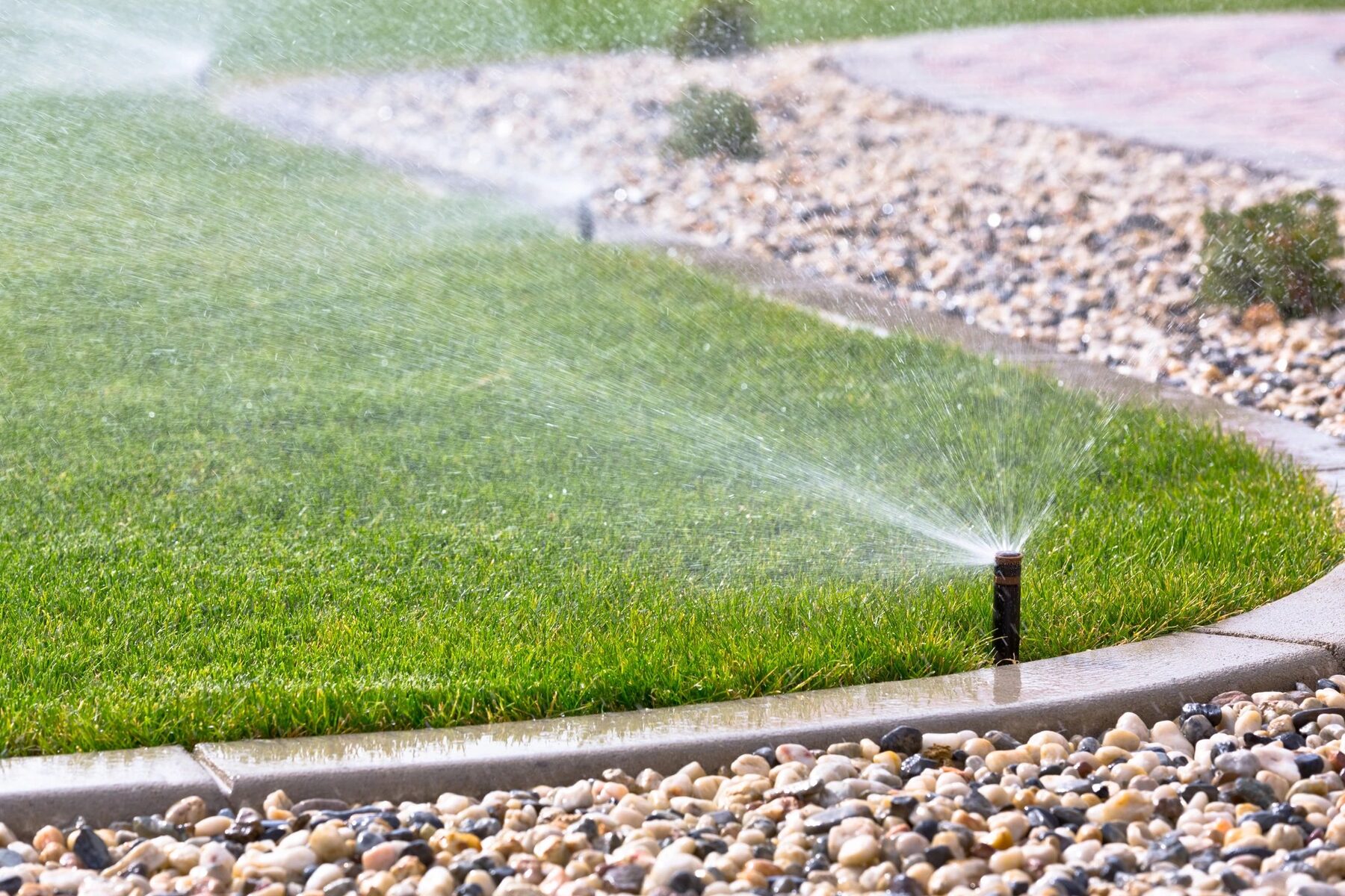 A healthy lawn being evenly watered by a sprinkler system